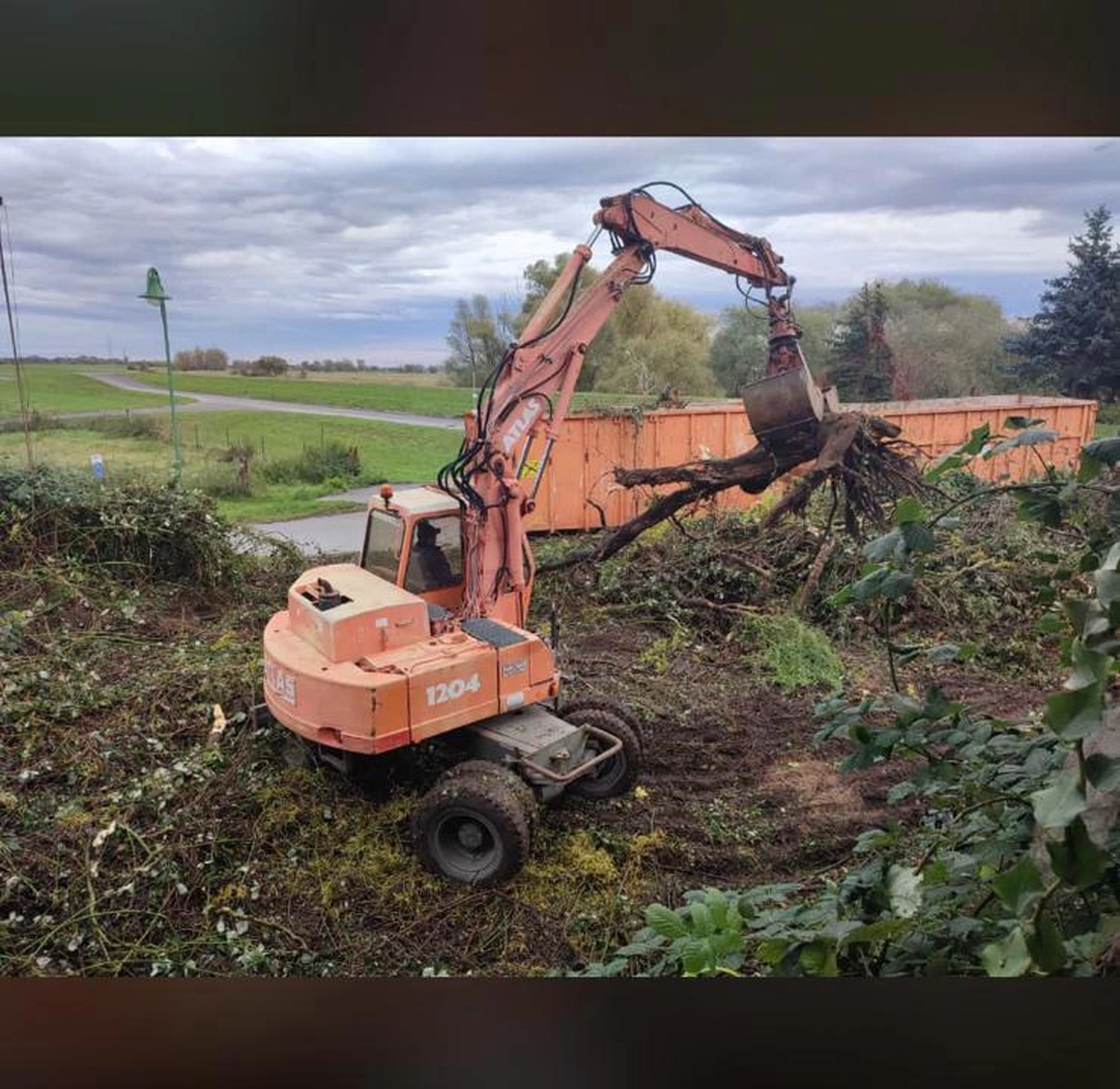 Stahlke - Tief- und Landschaftsbau - Die Maschine ist mit einem speziellen Greiferaufsatz am Arm ausgestattet, der hier speziell zum Entfernen von Baumwurzeln und Schutt eingesetzt wird.